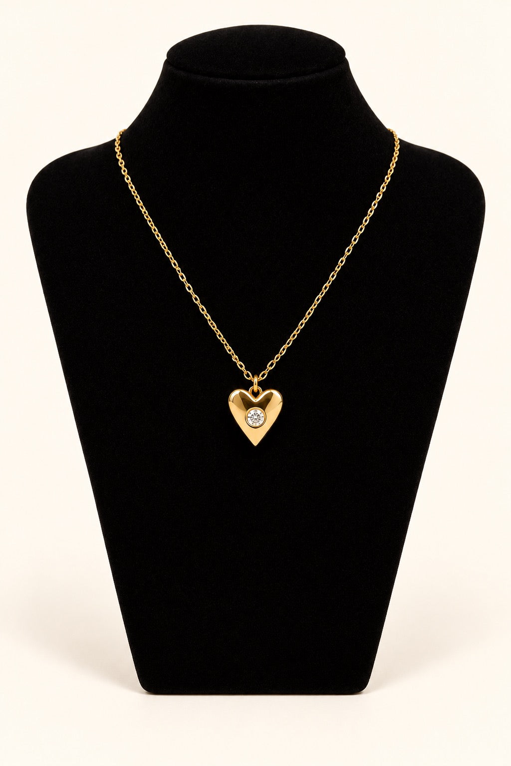 Michelle McDowell Loved Chain Necklace featuring an 18K gold-plated heart pendant with a sparkling clear center stone on a delicate gold chain, displayed on black velvet at Square 1 Boutique.