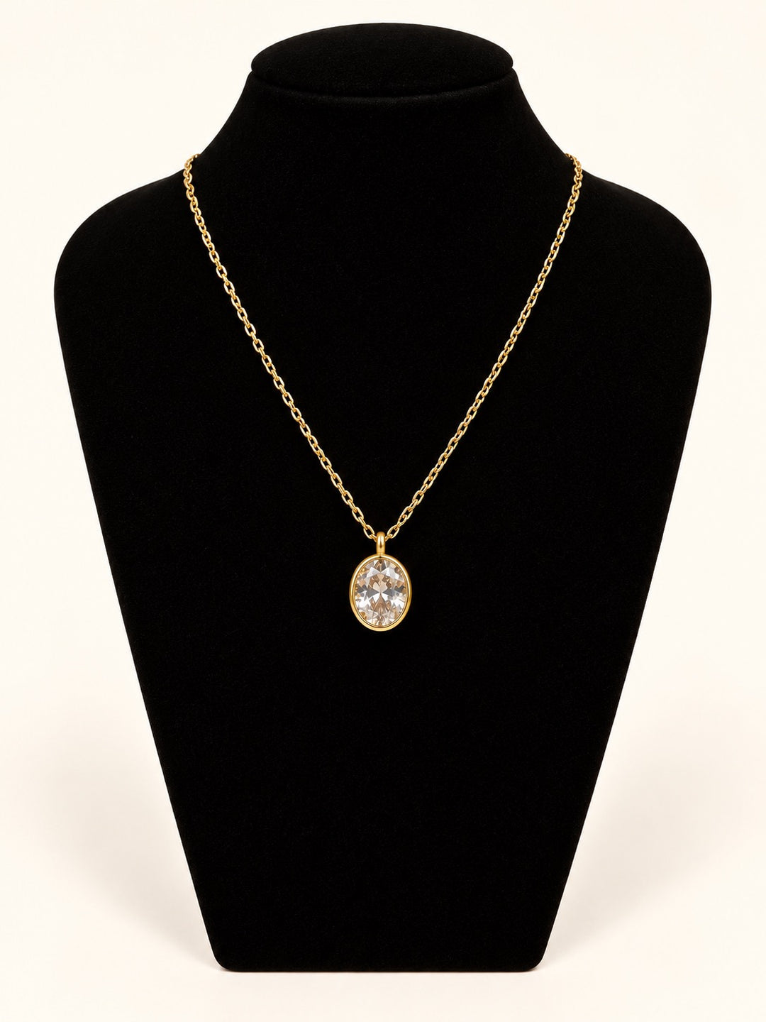 Michelle McDowell Valued Chain Necklace featuring a sparkling oval clear stone pendant in a polished gold setting on a delicate 18K gold-plated chain, displayed on black velvet at Square 1 Boutique.
