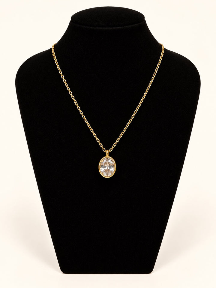 Michelle McDowell Valued Chain Necklace featuring a sparkling oval clear stone pendant in a polished gold setting on a delicate 18K gold-plated chain, displayed on black velvet at Square 1 Boutique.