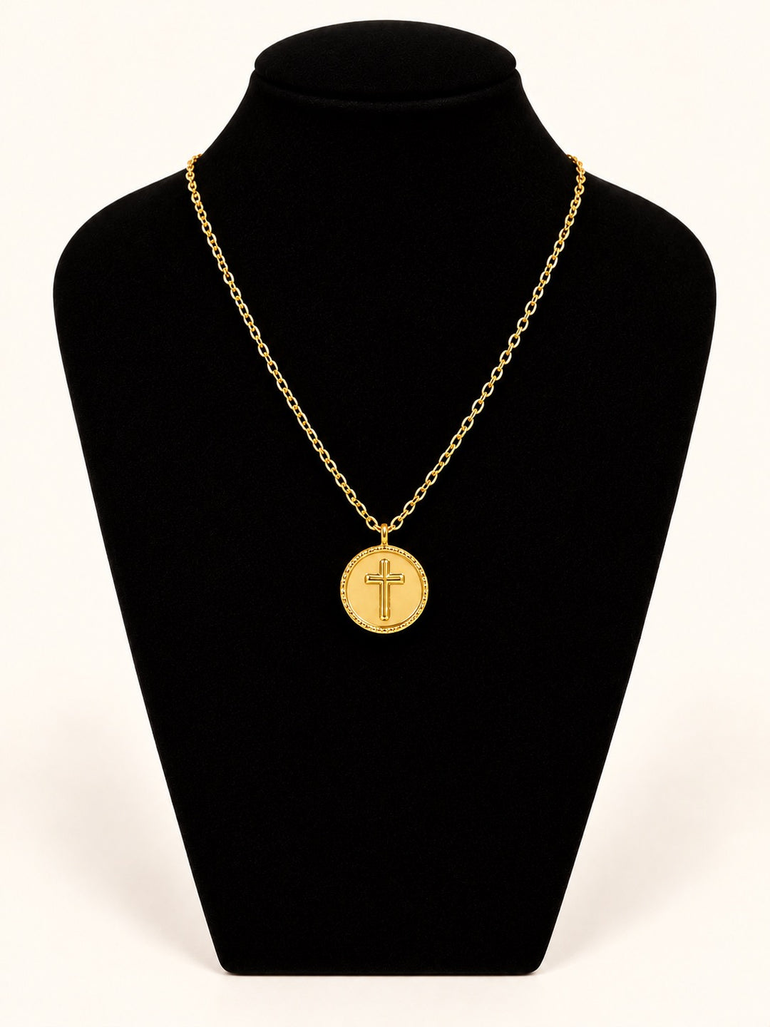 Michelle McDowell Saved Chain Necklace featuring a round gold cross pendant with decorative border on a delicate gold-plated link chain, displayed on black velvet at Square 1 Boutique.