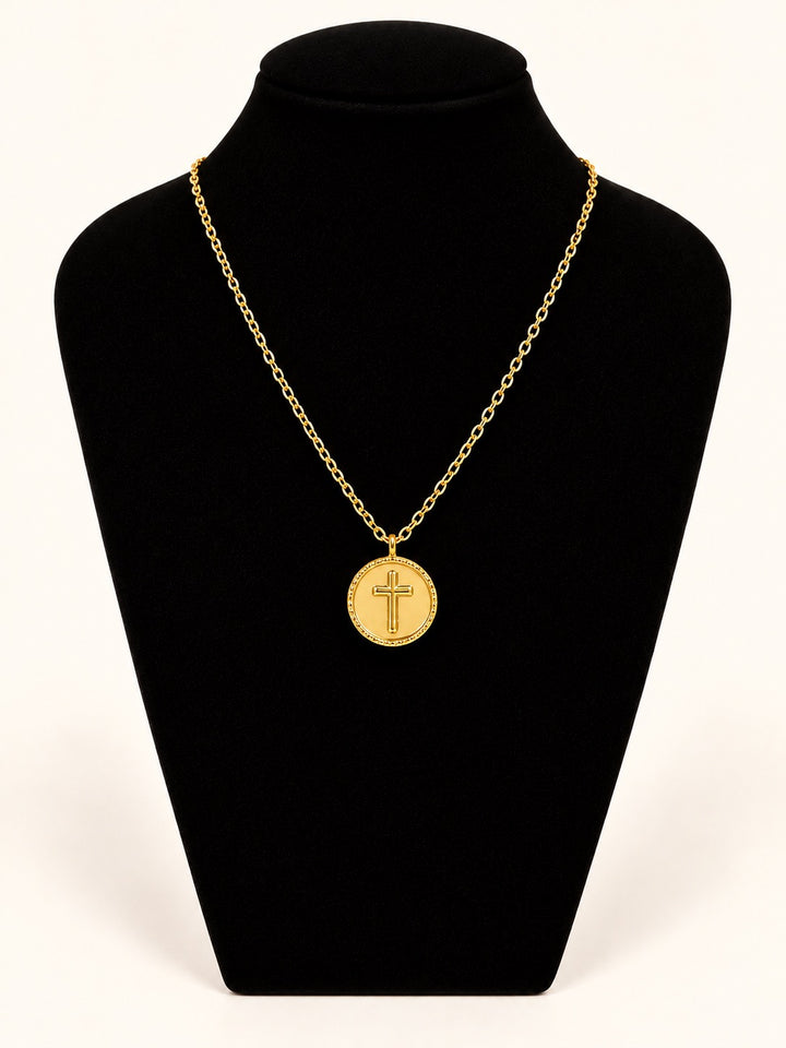 Michelle McDowell Saved Chain Necklace featuring a round gold cross pendant with decorative border on a delicate gold-plated link chain, displayed on black velvet at Square 1 Boutique.