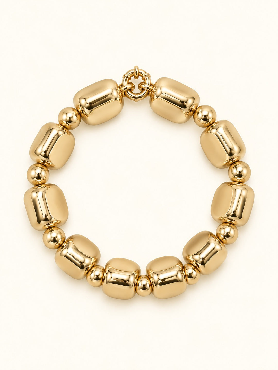 Rosalie Small Gold Beaded Bracelet featuring chunky rounded-square gold-tone beads with polished round spacer accents and a circular bracelet design on a cream studio background.