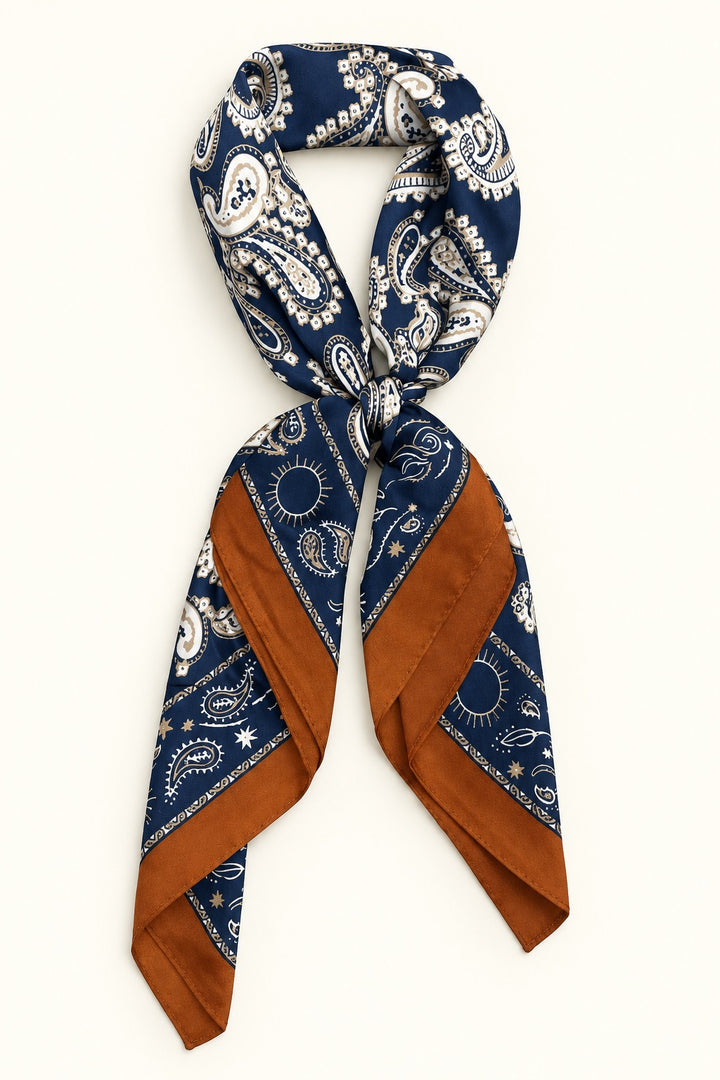 Navy paisley border scarf tied in a neck scarf style with cream paisley print and contrasting rust brown accents on a cream background.