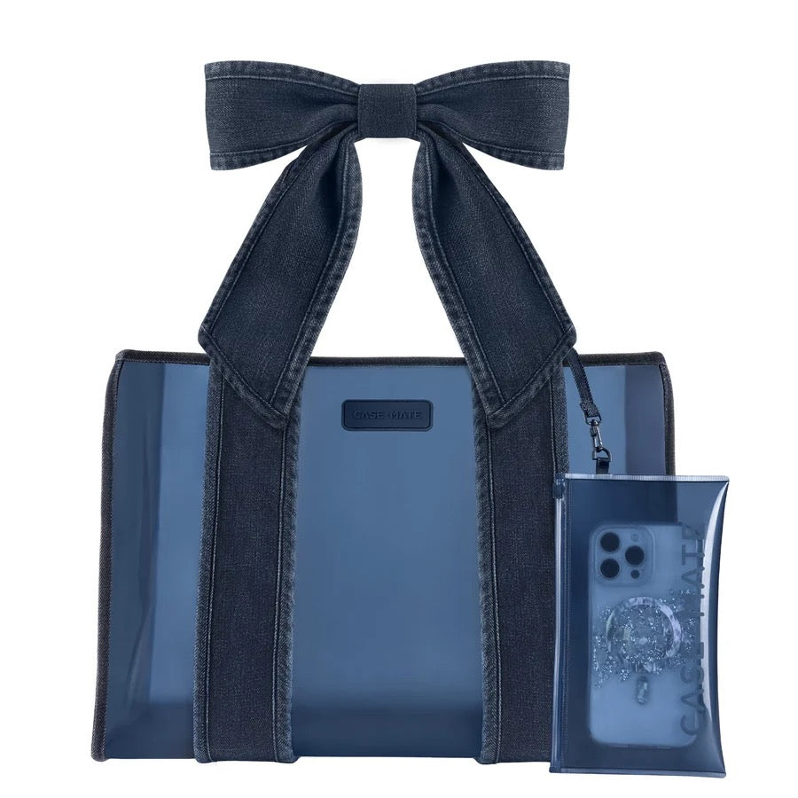A dark blue denim tote bag with matching denim shoulder straps and a large bow, shown alongside a matching translucent phone pouch on a plain white background.