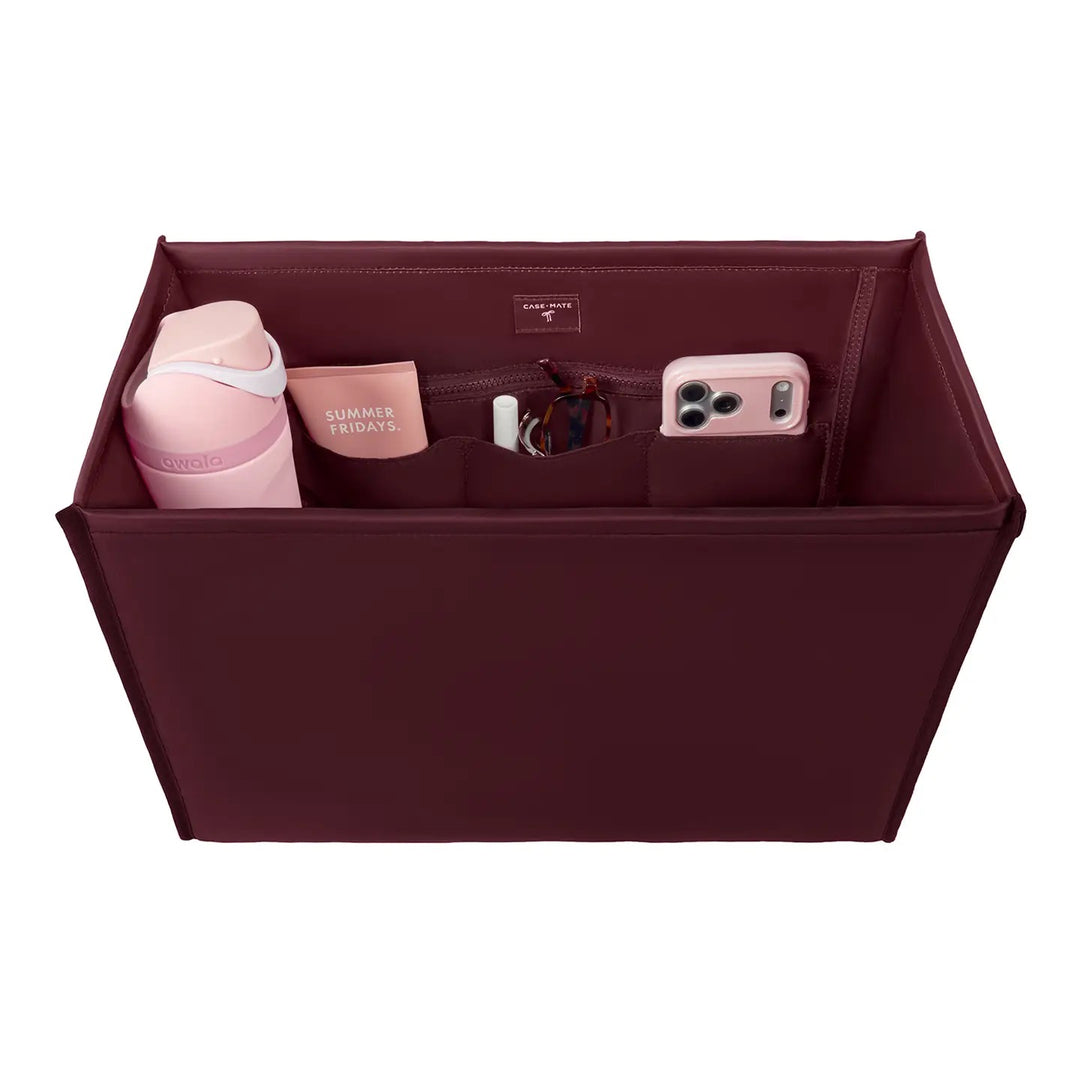 Case-Mate Classic Size Tote Organizer in Mulberry burgundy featuring six storage compartments, laptop pocket, water bottle holder, zippered pocket and key lanyard, displayed with everyday essentials on a white background.
