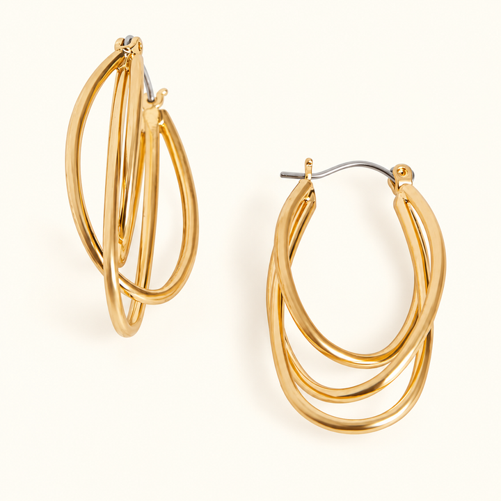 Gold-tone triple hoop earrings featuring three layered oval hoops, a polished finish, and hinged closures in a 1.5-inch design on a cream background.