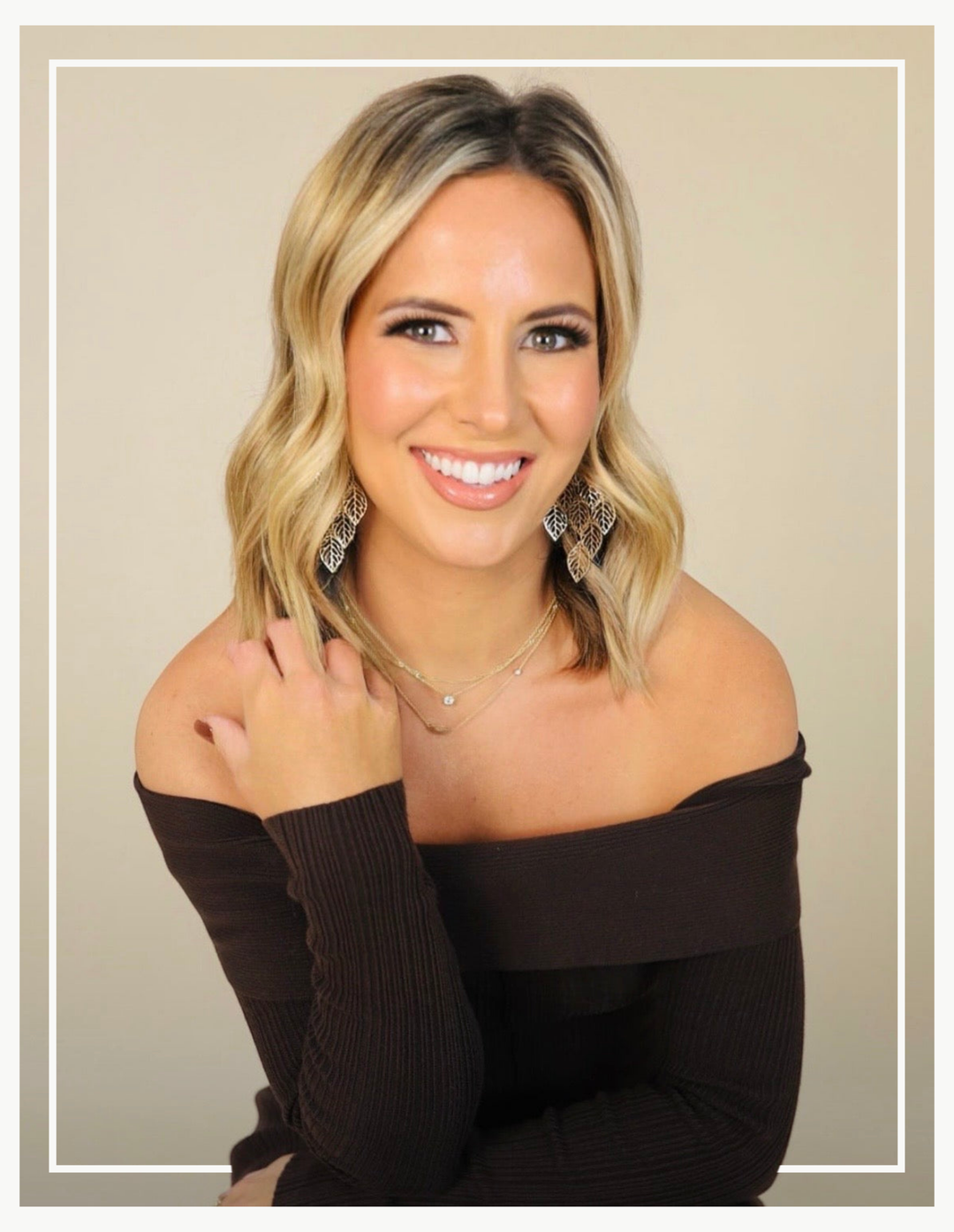 Woman wearing a black off-shoulder top against a beige background