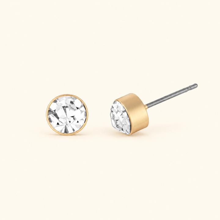 6mm clear crystal stud earrings shown from front and side angles, highlighting the round faceted stones, gold-tone bezel settings, and silver-tone posts.