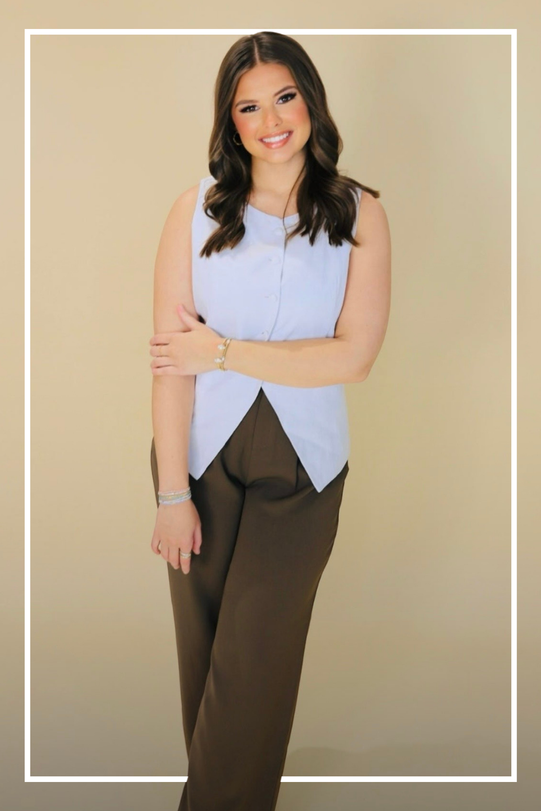 Woman wearing a light blue top and brown pants against a beige background | Model - Olivia | Square 1 Boutique 