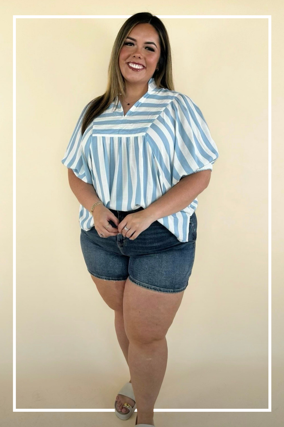 Woman wearing a blue and white striped shirt and denim shorts on a beige background | Model - Samantha | Square 1 Boutique