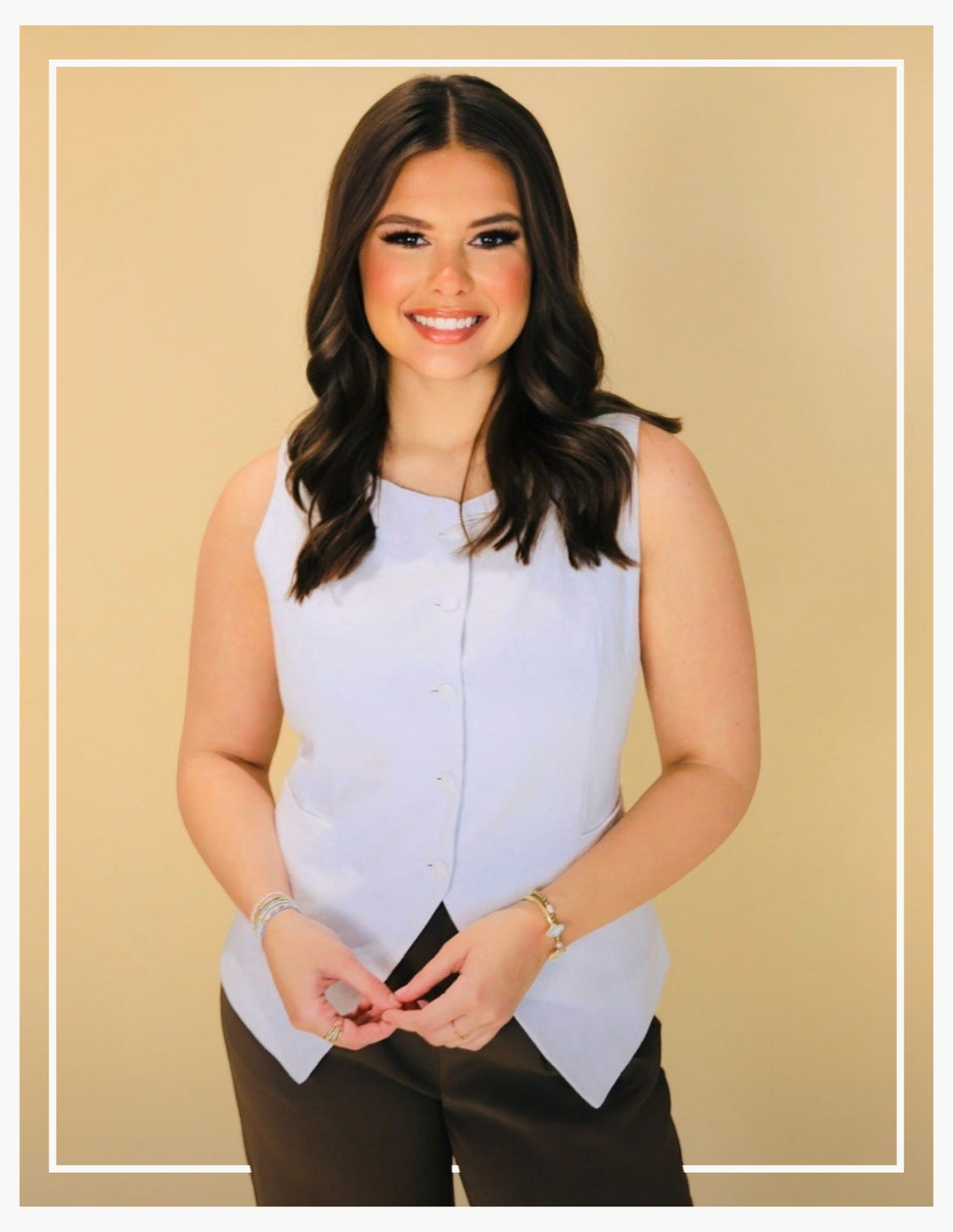 Woman wearing a light blue sleeveless top against a beige background