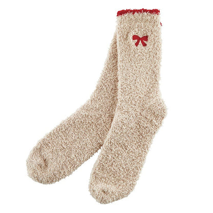 Beige fuzzy socks with a red bow on a white background