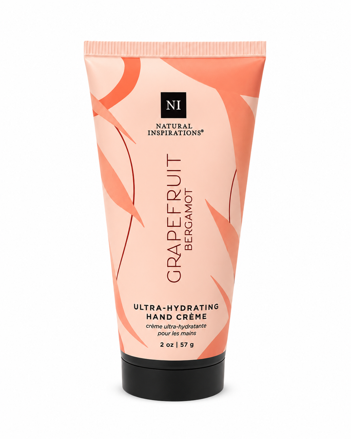 Natural Inspirations Grapefruit Bergamot Ultra-Hydrating Hand Crème (2 oz / 57 g) in a soft peach squeeze tube with coral botanical artwork and a black flip-top cap, photographed on a white studio background.