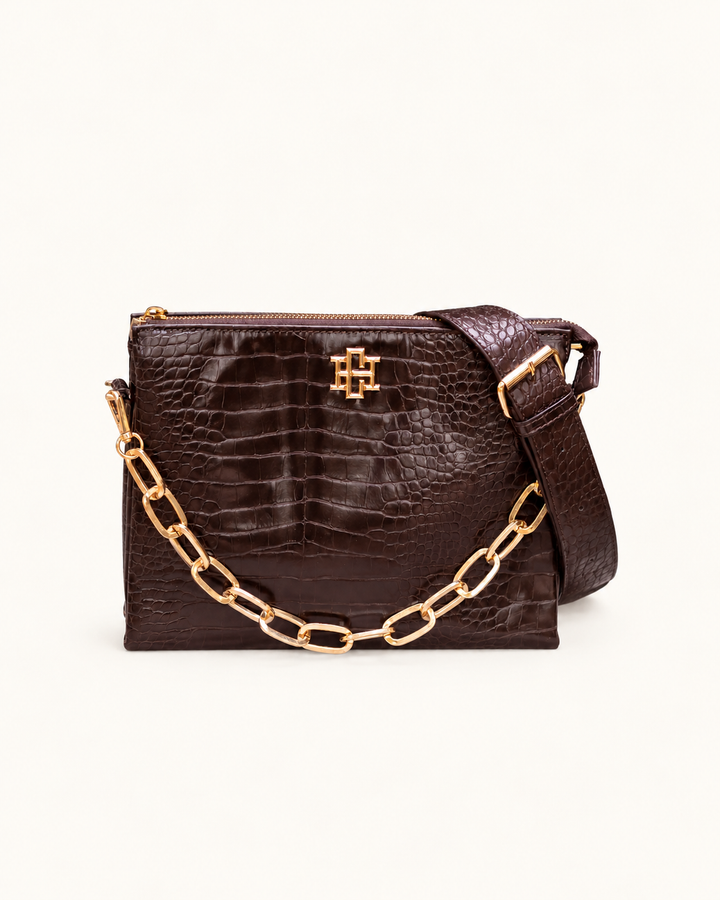 Caroline Hill Ariana chocolate croc-embossed crossbody bag with gold logo, removable chain accent, and adjustable shoulder strap.