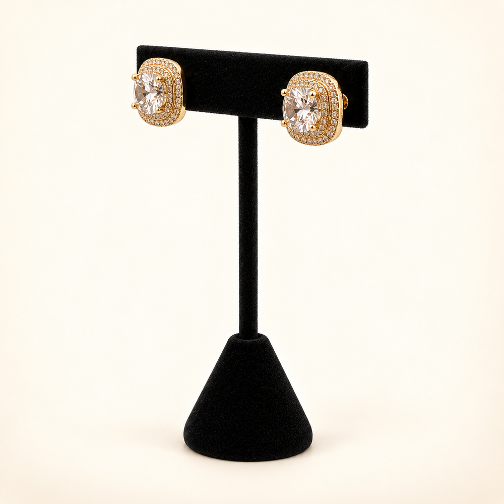 Angled view of gold square CZ stud earrings featuring clear center stones and sparkling multirow halos on a black velvet stand.