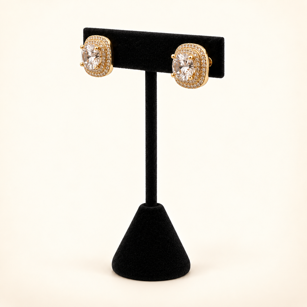 Angled view of gold square CZ stud earrings featuring clear center stones and sparkling multirow halos on a black velvet stand.