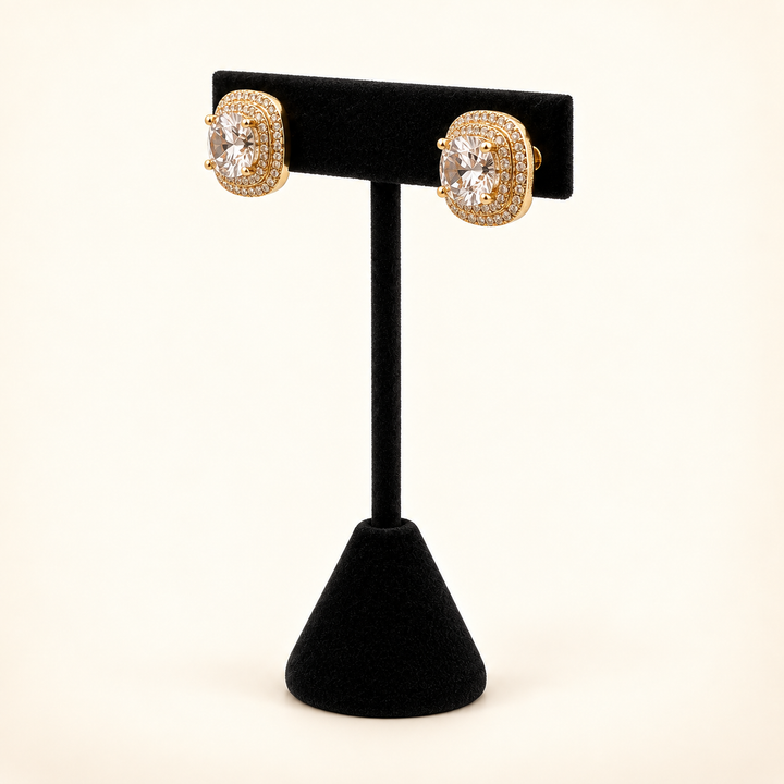Angled view of gold square CZ stud earrings featuring clear center stones and sparkling multirow halos on a black velvet stand.