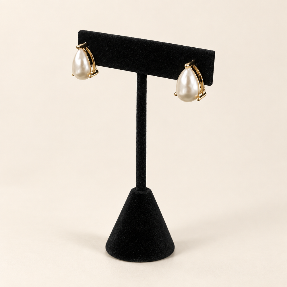 Angled view of ivory teardrop pearl earrings showing their dimensional shape and delicate gold-tone settings.