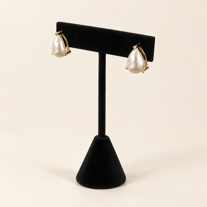 Angled view of ivory teardrop pearl earrings showing their dimensional shape and delicate gold-tone settings.