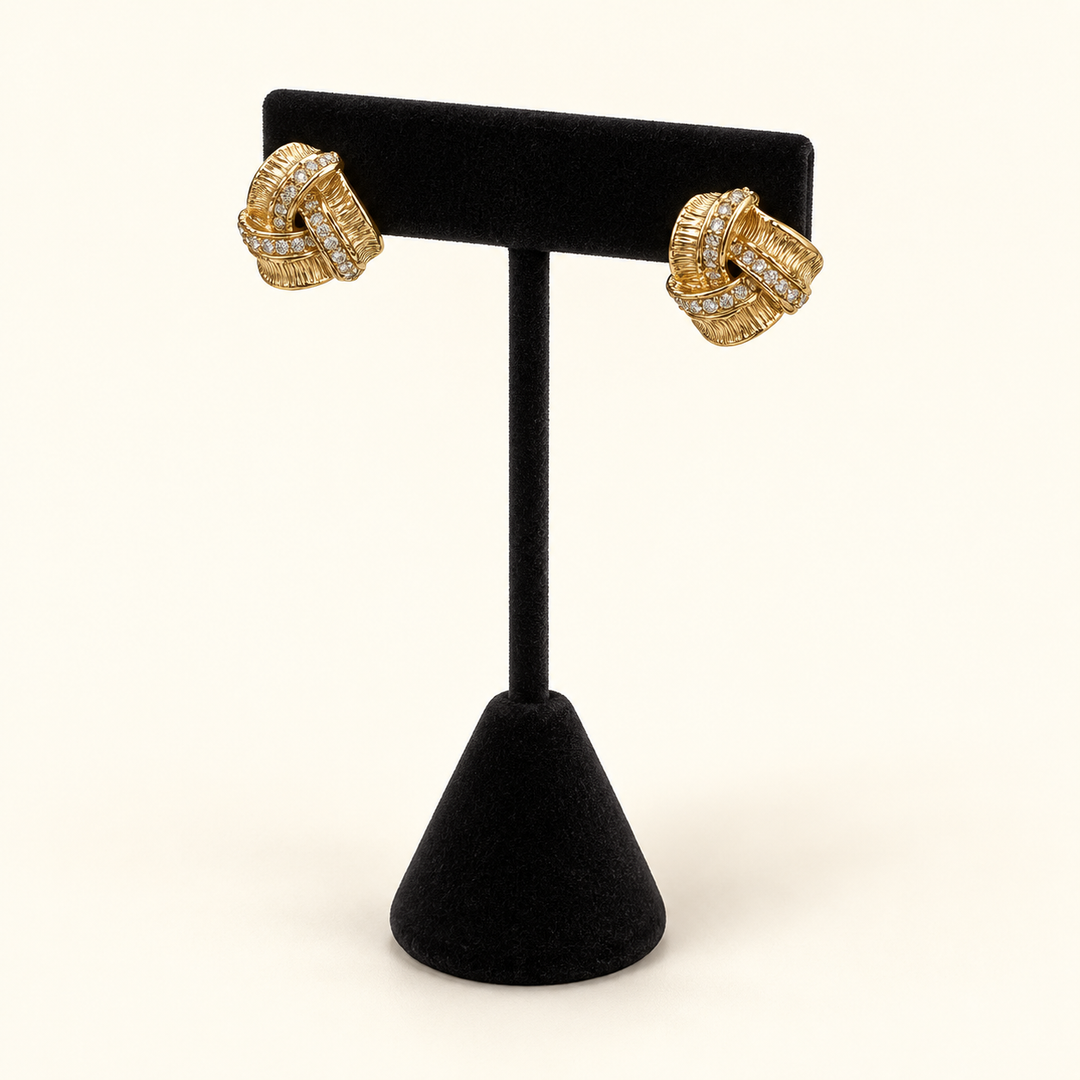 Angled view of gold-tone pavé love knot earrings showing the textured intertwined design and sparkling stone accents.
