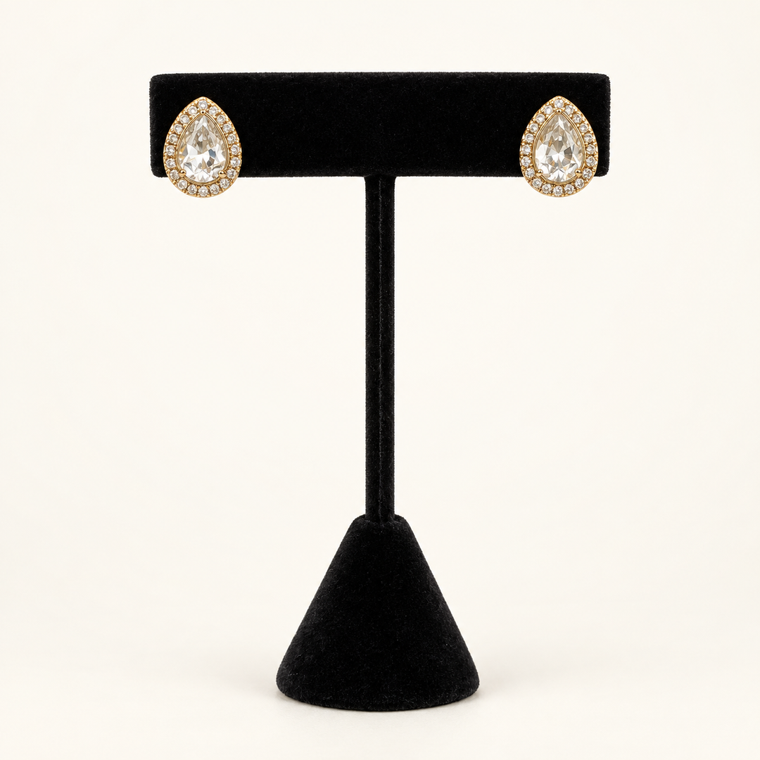 Front view of gold teardrop stud earrings featuring clear pear-cut stones with sparkling halos on a black velvet stand.