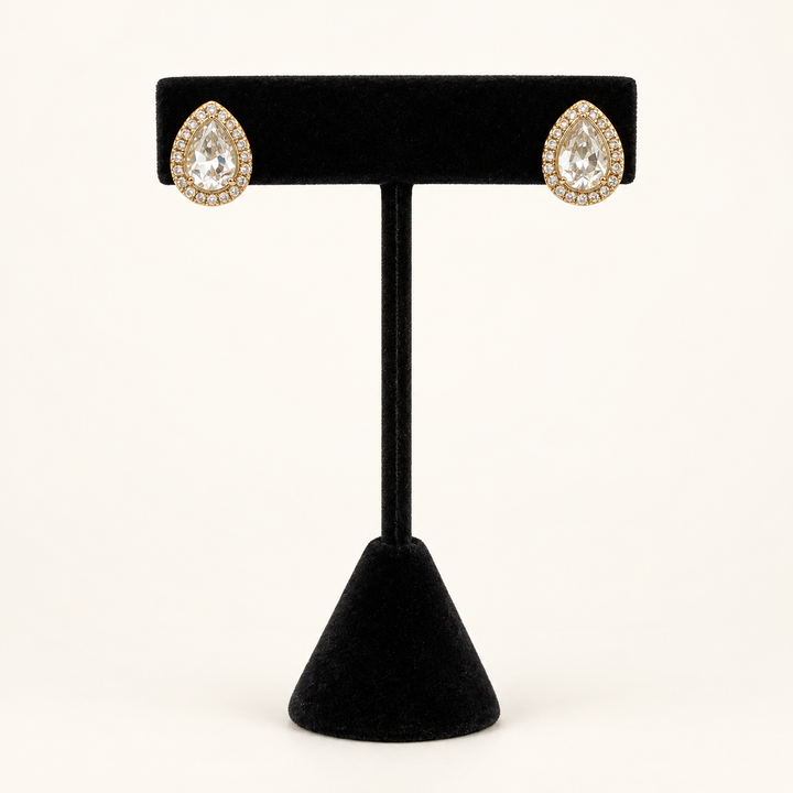 Front view of gold teardrop stud earrings featuring clear pear-cut stones with sparkling halos on a black velvet stand.