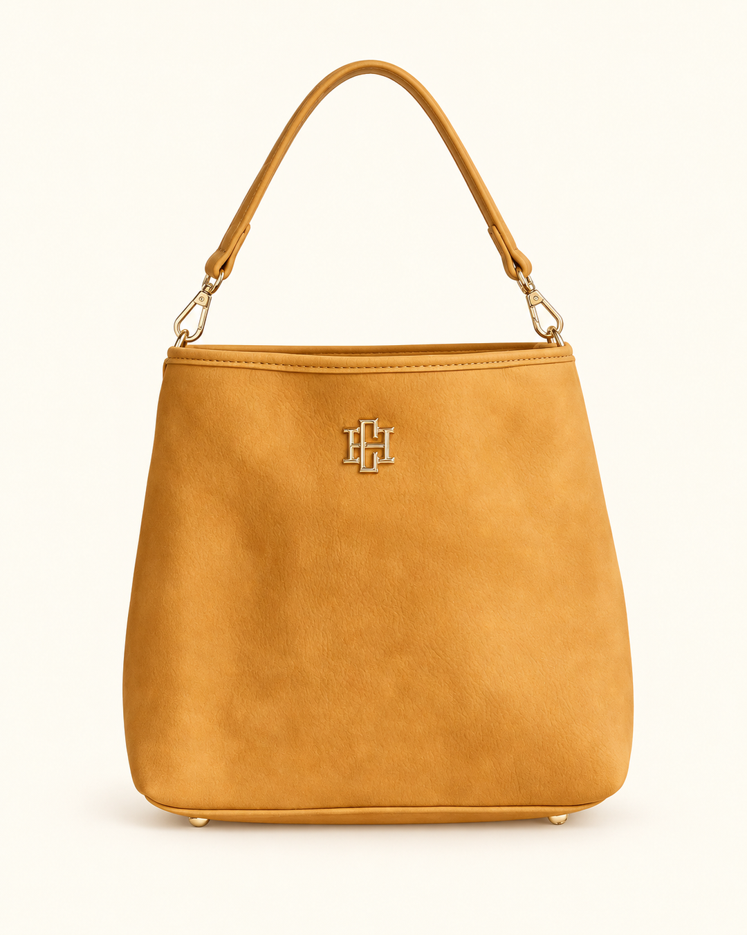 Front view of the mustard faux-suede Alexandra Bucket Bag by Caroline Hill with a removable short handle and gold logo hardware.