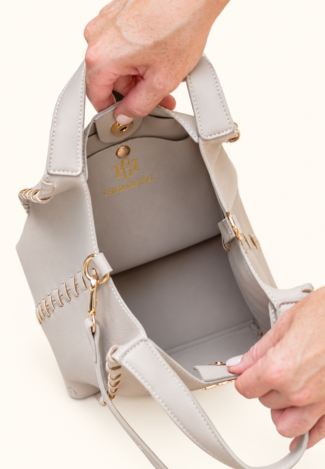 Interior view of the Caroline Hill Allison Tote in Stone showing its spacious compartment, magnetic closure, gold logo, and removable crossbody strap.