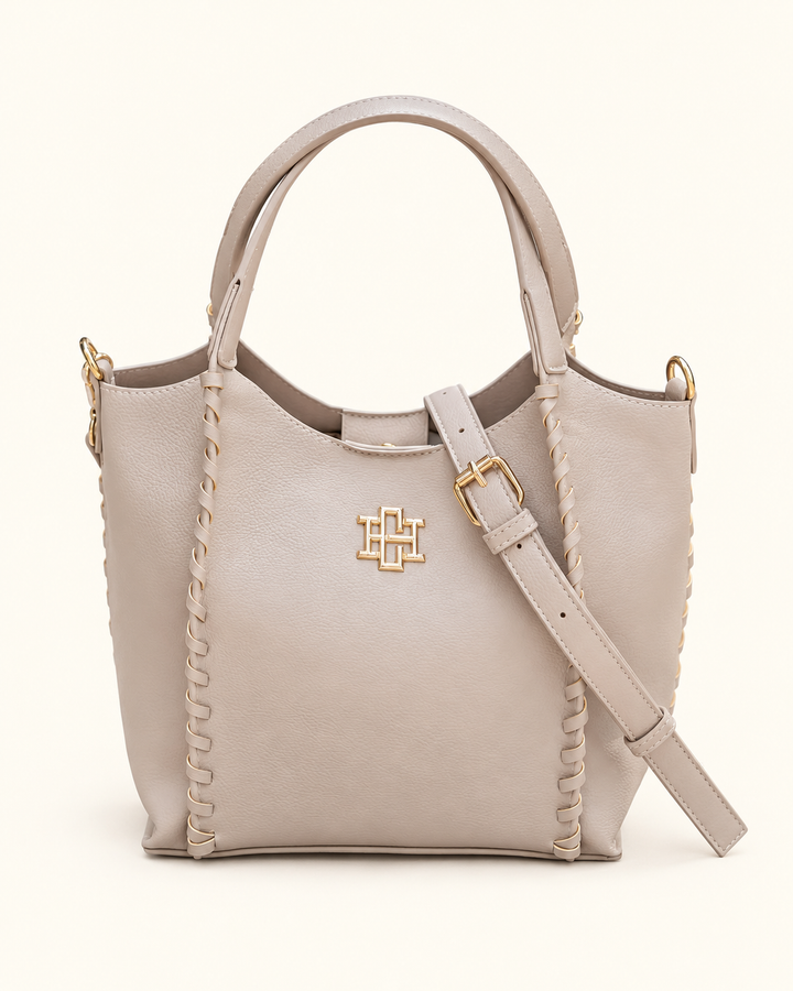 Front view of the Caroline Hill Allison Tote in Stone with whipstitch detailing, gold logo hardware, top handles, and an adjustable crossbody strap.