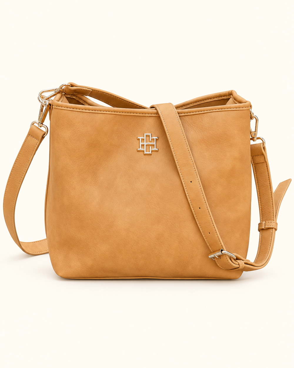 Front view of the Caroline Hill Alexandra Bucket Bag in mustard faux suede with gold logo hardware and an adjustable crossbody strap.