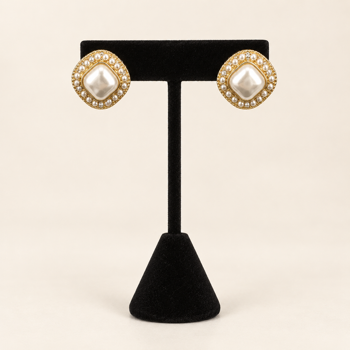 Front view of Pearl Caviar Square Earrings with pearl centers and gold-tone pearl borders displayed on a black velvet stand.