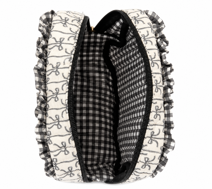 Open Simply Southern Black Bow Quilted Cosmo Bag featuring a black bow print exterior, ruffle trim, black zipper, and spacious black-and-white gingham lined interior with organizational pockets on a clean white studio background.