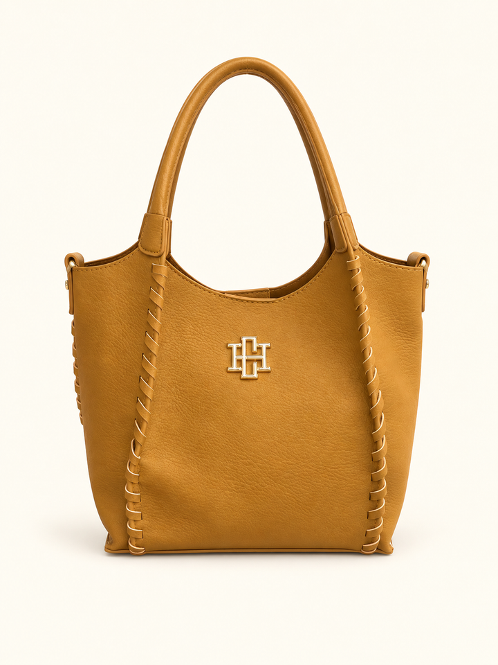 Front view of the Caroline Hill Allison Tote in Mustard featuring whipstitch detailing, dual top handles, gold logo hardware, and a structured mini-tote silhouette.