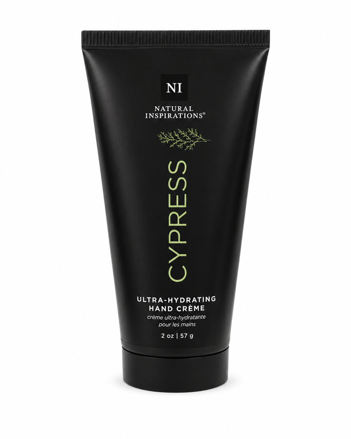 Natural Inspirations Cypress Ultra-Hydrating Hand Crème (2 oz / 57 g) in a matte black squeeze tube with sage green lettering and botanical details, featuring a black flip-top cap on a clean white studio background.