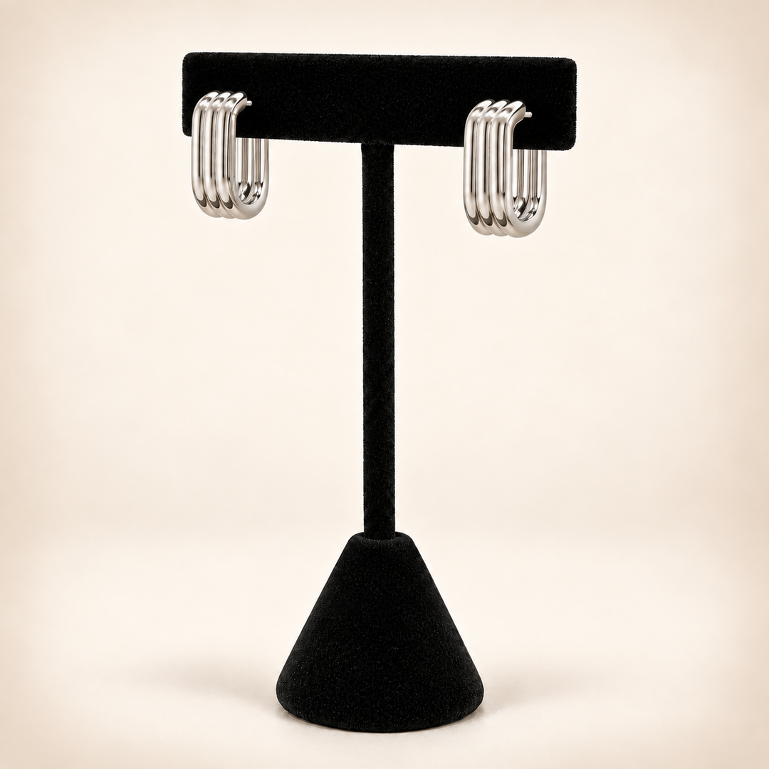 Rear view of silver four-row hoop earrings with post and butterfly backs displayed on a black velvet stand.