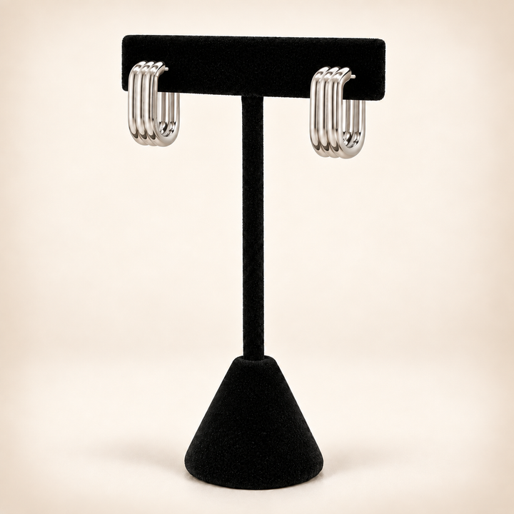 Rear view of silver four-row hoop earrings with post and butterfly backs displayed on a black velvet stand.