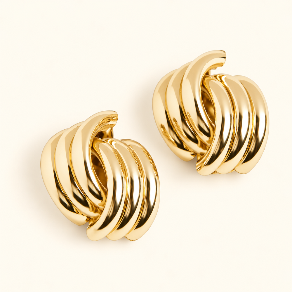 Gold-tone chunky knot hoop earrings featuring polished, intertwined curved bands in a 0.5-inch design on a cream background.
