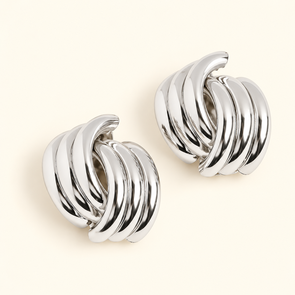 Silver-tone chunky knot hoop earrings featuring polished, layered curved bands in a 0.5-inch design on a cream background.