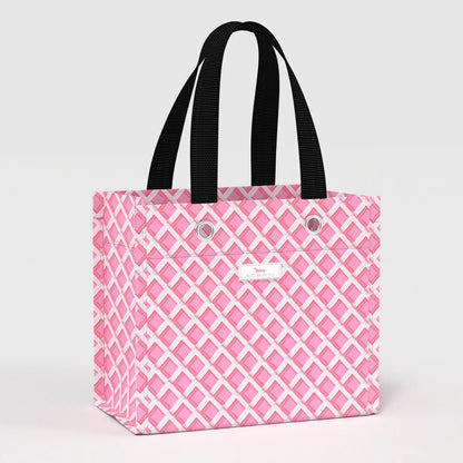 Angled view of Gift Bag Small in Garden Gate pink lattice pattern, structured reusable gift bag with black carry handles.