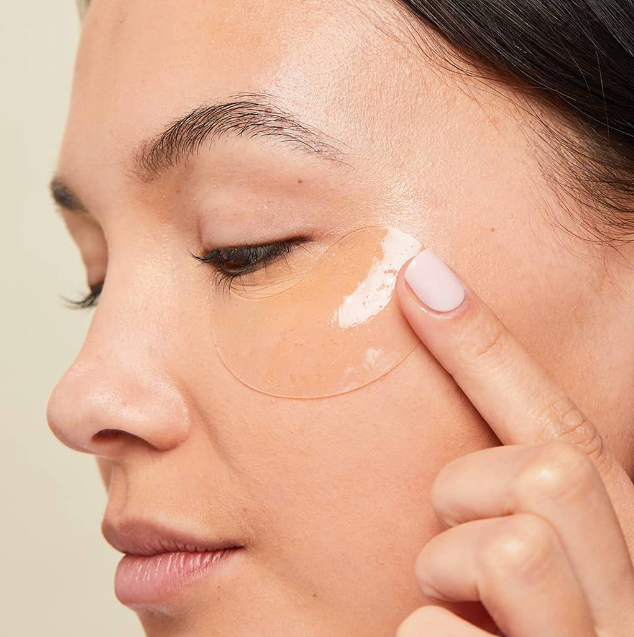 Person applying a patch to their face with a neutral background