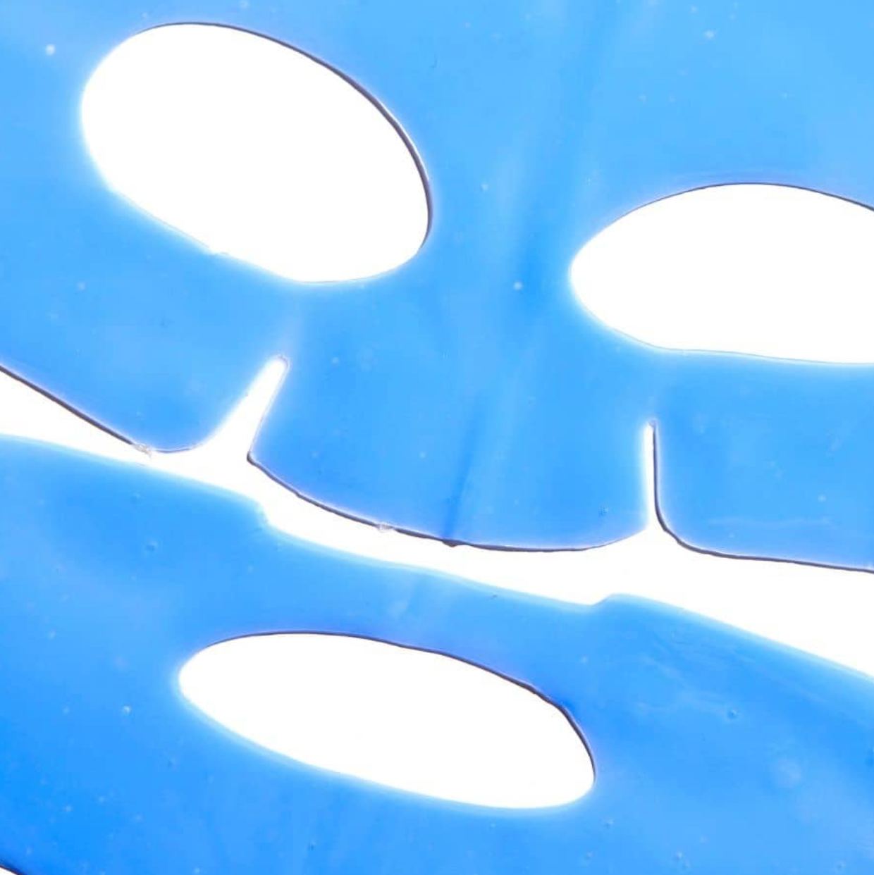 Close-up of a blue plastic component with circular cutouts on a blue background