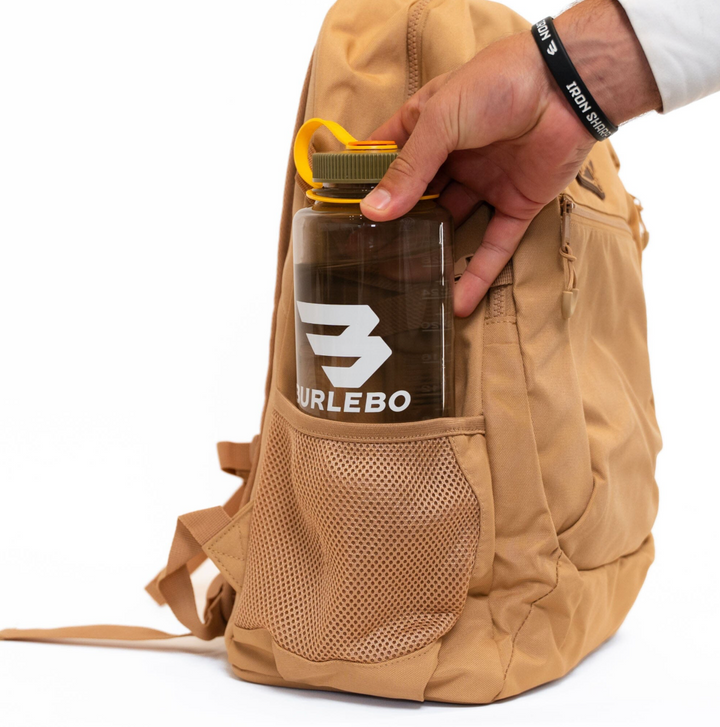 Burlebo Coyote Tan backpack with a large insulated tumbler securely stored in the expandable side mesh pocket, demonstrating everyday carrying capacity.