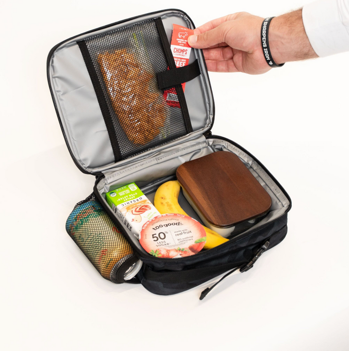 Open Burlebo Black Camo lunchbox displaying the insulated interior, mesh storage pocket, and spacious compartment holding lunch containers, snacks, and a drink.