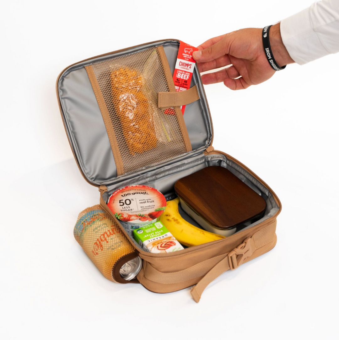 Open Burlebo Coyote Tan lunchbox displaying the insulated interior, mesh storage pocket, and spacious compartment holding lunch containers, snacks, and a drink.