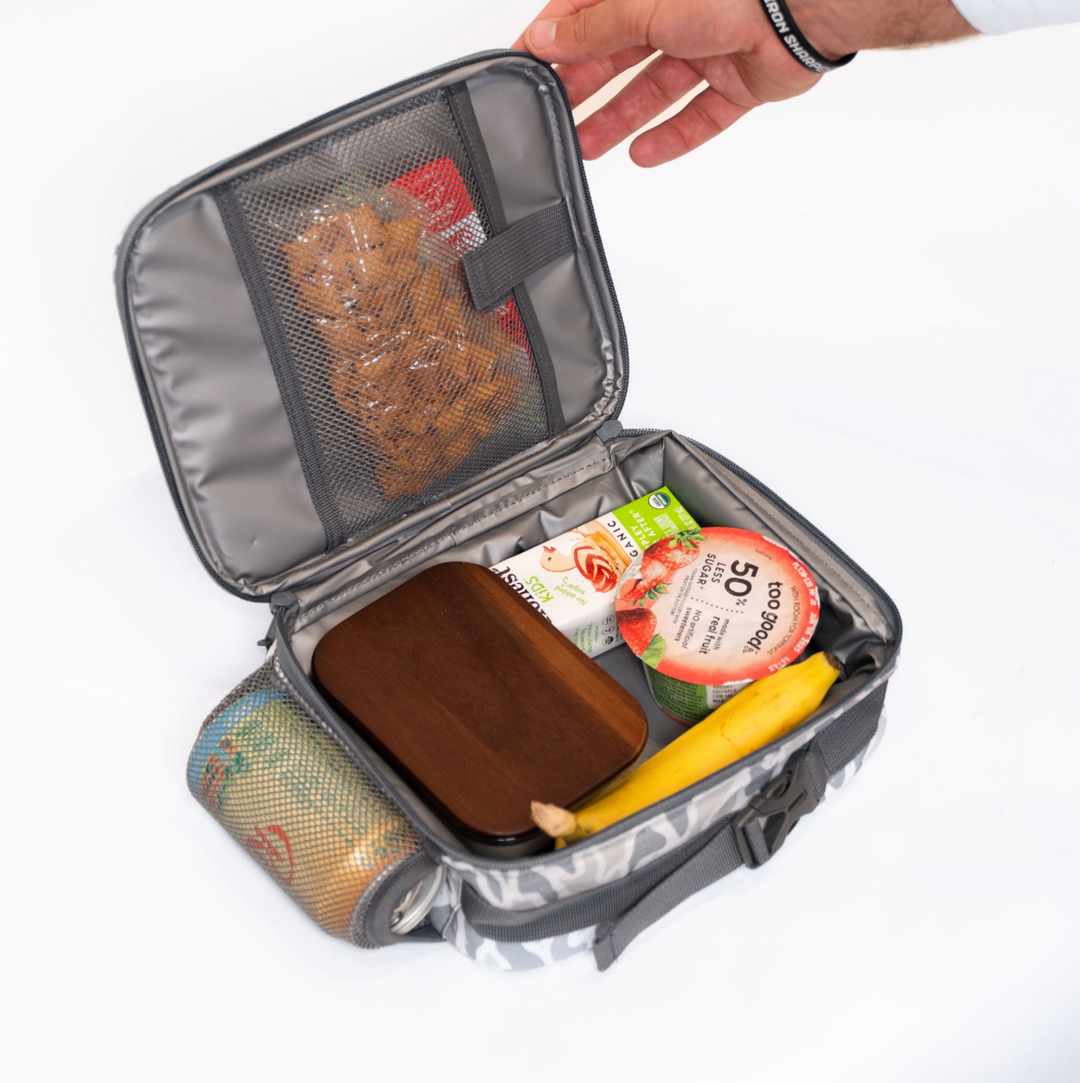 Open Burlebo White Camo lunchbox displaying the insulated interior, mesh storage pocket, and spacious compartment holding lunch containers, snacks, and a drink.