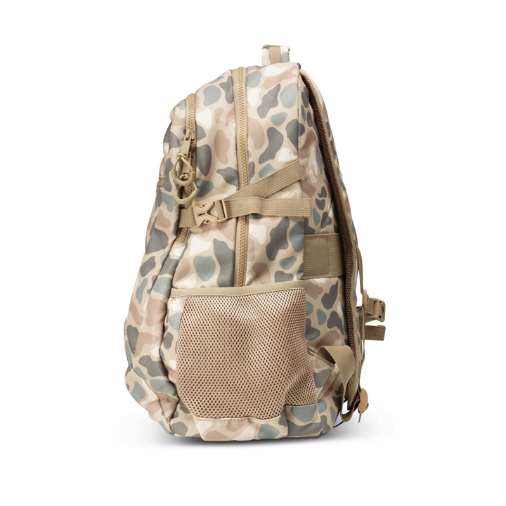 Side profile of the Burlebo Pintail Camo backpack showing the expandable mesh water bottle pocket and slim everyday design.
