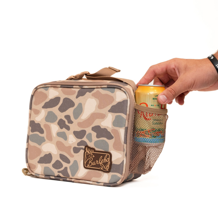 Burlebo Pintail Camo lunchbox featuring a side mesh pocket holding a beverage can, durable insulated construction, and convenient carry handle on a white studio background.