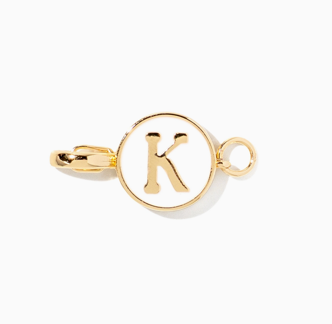 A gold initial charm link featuring a circular face with a raised letter &