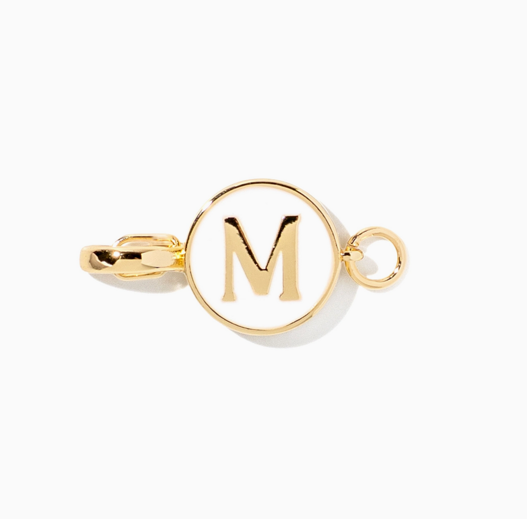 A gold initial charm featuring the letter &