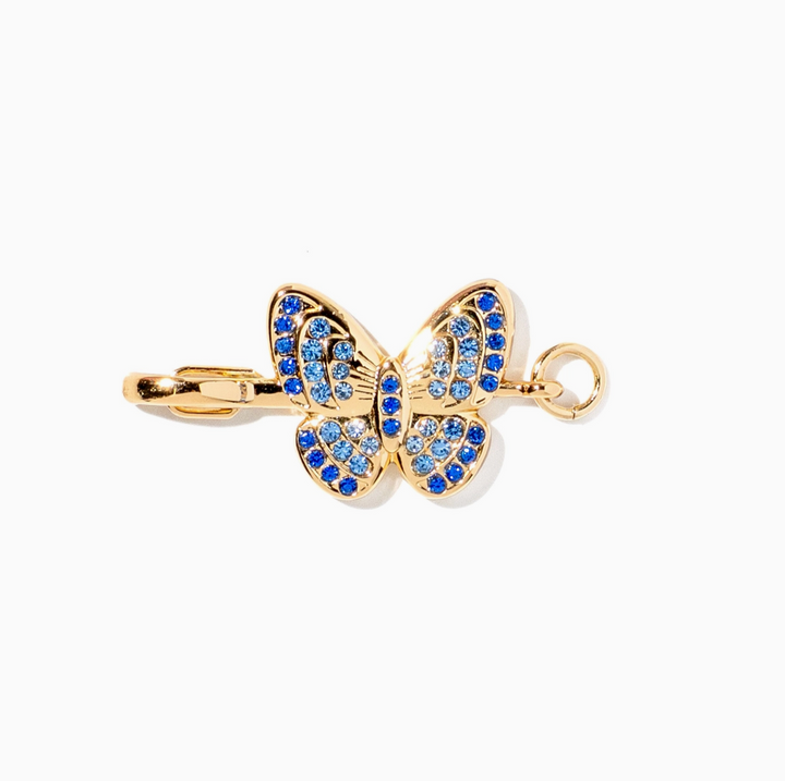 Gold butterfly pendant charm embellished with blue and clear rhinestones, shown on a plain white background.